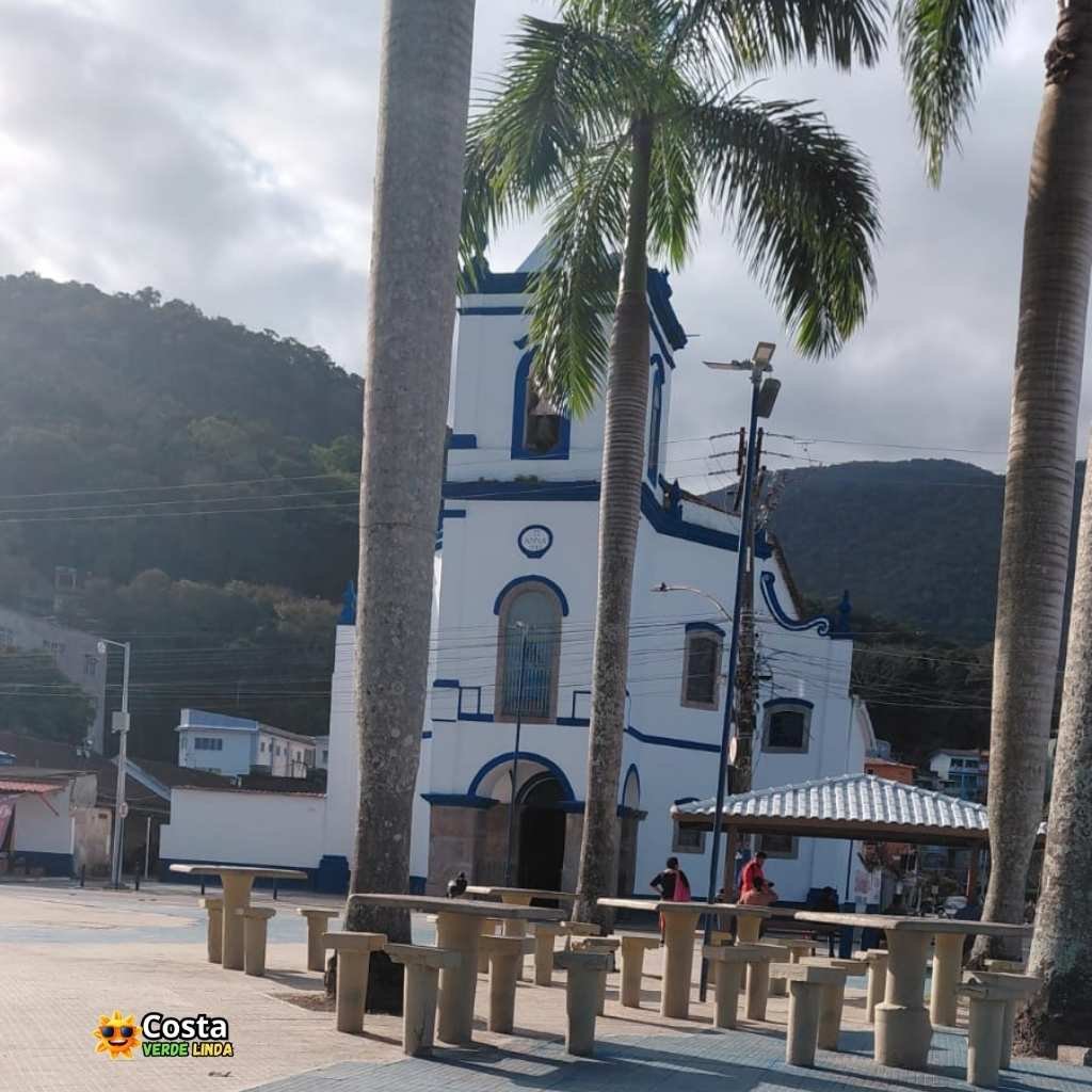 Vista lateral da Igreja Nossa Senhora de Santana mostrando a torre sineira e o adro arborizado em Itacuruçá